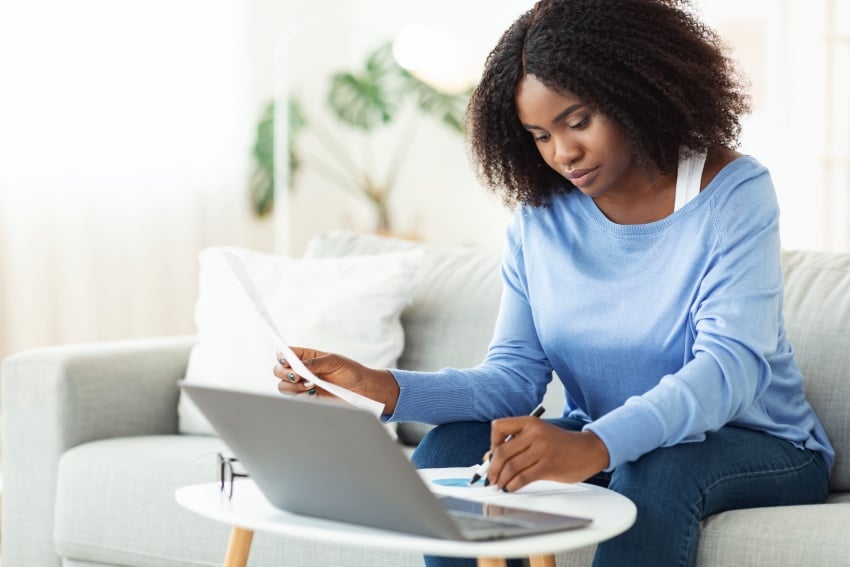 woman signing papers working on laptop at home c2u3vje woman signing papers working on laptop at home c2u3vje